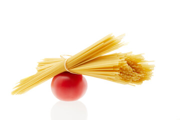 Raw spaghetti and red tomato isolated one white background.