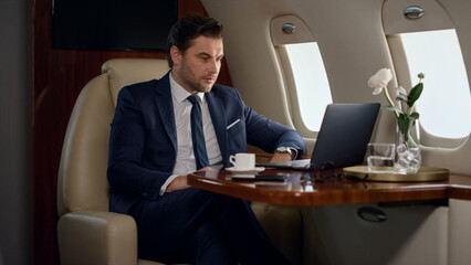 Serious businessman videocalling partner in private jet. Focused ceo talk online