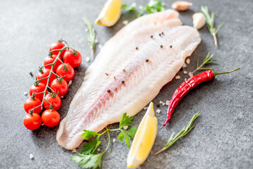 Fresh raw white fish fillet Pangasius with spices and lemon on a stone background.