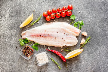 Fresh raw white fish fillet Pangasius with spices and lemon on a stone background.