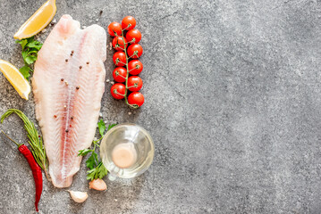 Fresh raw white fish fillet Pangasius with spices and lemon on a stone background with copy space for your text - obrazy, fototapety, plakaty