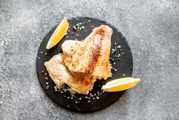 Baked white fish fillet Pangasius with spices and lemon on a stone background