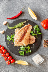Baked white fish fillet Pangasius with spices and lemon on a stone background