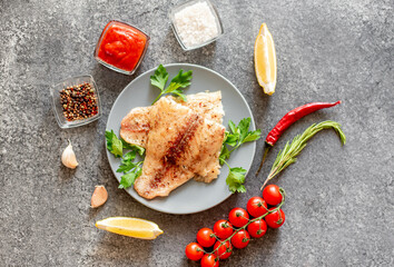 Baked white fish fillet Pangasius with spices and lemon on a stone background