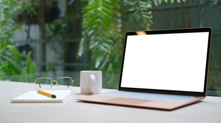Mock up computer laptop with blank screen on wooden table at comfortable workplace.