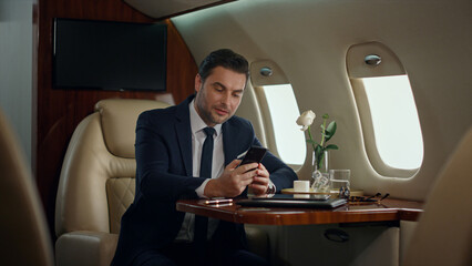 Busy man finishing phone call in luxury jet. Focused manager drinking coffee
