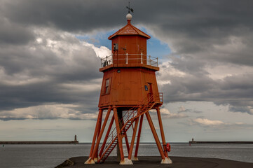 The old, red, wooden Herd Groyne Lighthouse in South Shields, stands out against the cloudy sky
