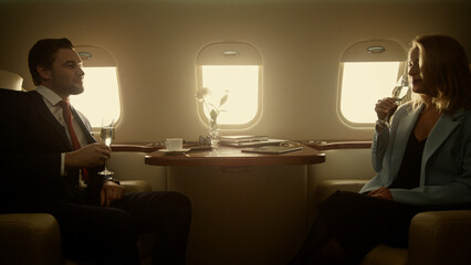 Luxury couple flying jet in golden sunlight. Successful business partners rest