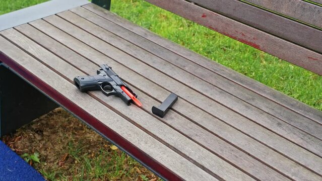 Plastic Broken Pistol Gun Toy for Kids Left on Playground Bench