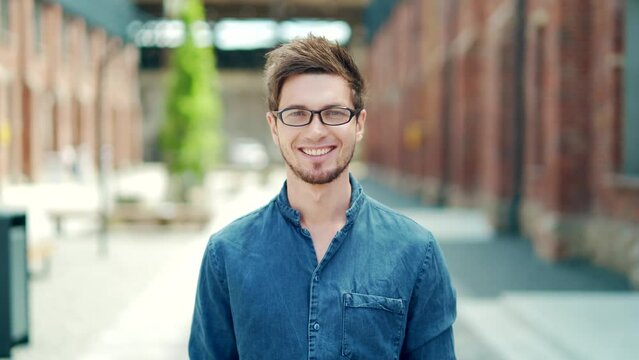 portrait handsome young male student in casual denim shirt and glasses looking at camera on urban university campus background. outside. Happy glad stylish caucasian guy. cheerful smiling, laughing