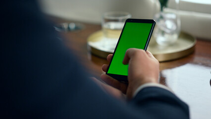 Man hand scrolling green smartphone screen closeup. Businessman using chroma key