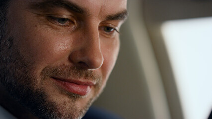 Successful businessman working jet closeup. Cheerful bearded man looking window