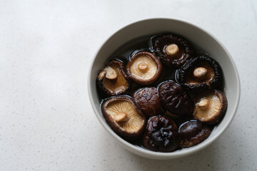 some fresh raw shiitake soaked in water in bowl on table. edible mushroom
