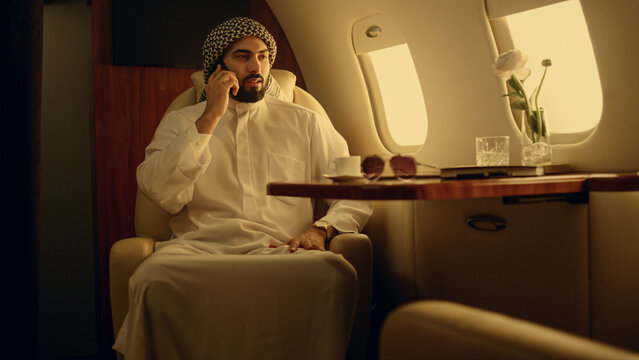 Professional speaking mobile phone in private jet. Businessman discussing work