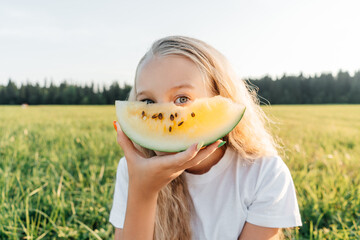 Preteen girl with piece of yellow watermelon.
