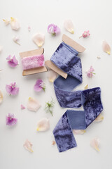 pink and navy blue velvet ribbon on white background with flower petals next to it, top view. Decor for bouquets