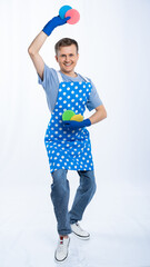 a man in a blue apron, rubber gloves, an orange t-shirt, jeans and white sneakers holds sponges for...