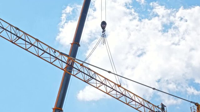 Construction Site Worker Performing Maintenance of High Metal Tower Crane