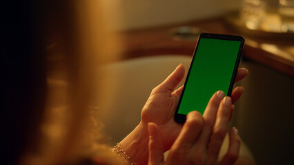 Hand touching greenscreen smartphone closeup. Woman swiping cellphone on jet.