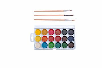 Naklejka premium Multicolored aquarelle paints in paint box with brushes on white background.