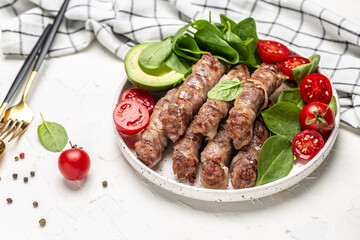 chevapchichi or Kofta kebab, Bacon wrapped minced meat with spinach, avocado and cherry tomato, Healthy fats, clean eating for weight loss. Keto paleo diet menu, top view