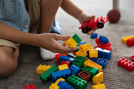 Little toddler boy playing with colorful plastic blocks at home building creative game, imagination