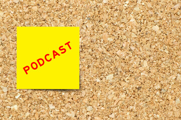 Yellow note paper with word podcast on cork board background with copy space