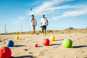 Tourists play an active game, petanque on a sandy beach by the sea - Group of young people playing...