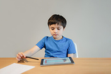 Naklejka premium School kid studying online with teacher,Kid doing homework on tablet, Child boy using digital pad searching information on internet, Home schooling,E-learning online education,Children with technology