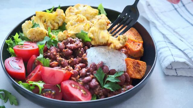 Baked vegetables buddha bowl. Sweet potato, cauliflower, tomato and bean salad. Vegan recipe.
