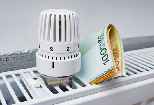 Thermostat with Euro cash on a radiator heating at home. Expensive heating costs symbolic image.