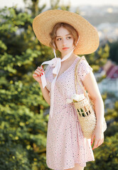 Close up portrait of a sweet blonde in a straw hat posing on a background of the city.