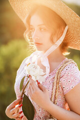 Close up portrait of a pretty blonde in a straw hat at the sunset