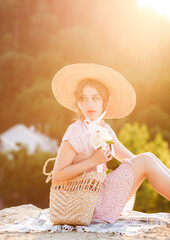 Close up portrait of a sweet blonde in a straw hat at the sunset