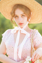 Close up portrait of a sweet blonde in a straw hat at the sunset