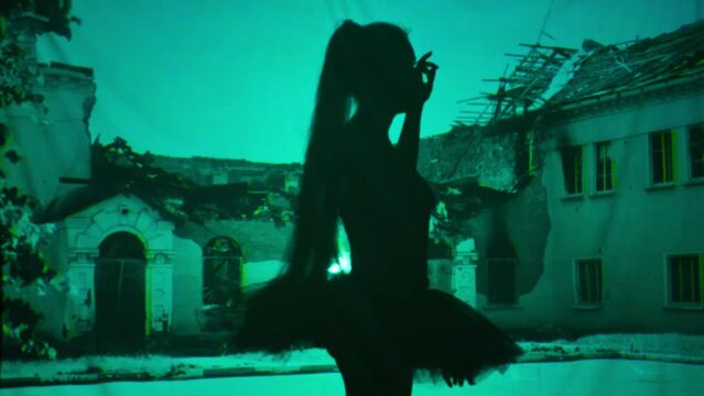Side view silhouette of slim female ballet dancer walking at background of bombed ruins photo dancing. Unrecognizable performer performing at background of ruined building picture