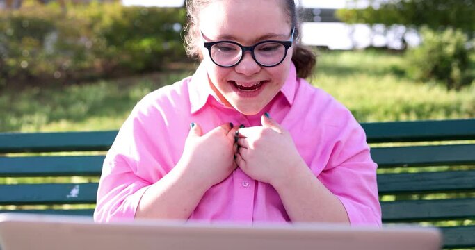 Teenage girl with down syndrome sitting on bench making video call
