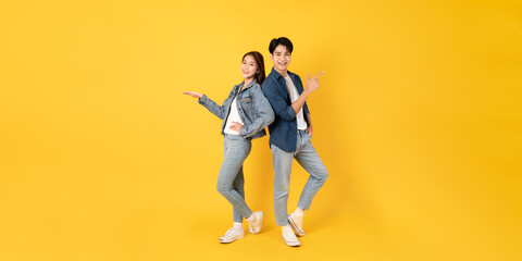 Fototapeta na wymiar Two Young good looking asian couple using isolated on yellow background presenting to copy space feeling excited
