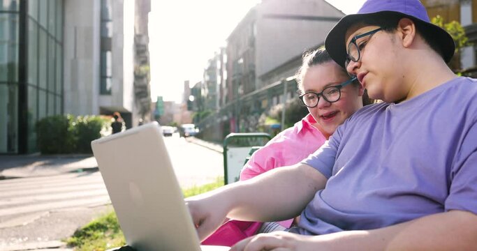 Brother and sister using laptop sitting in the city
