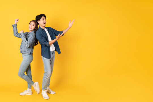 Two Young good looking asian couple using isolated on yellow background presenting to copy space