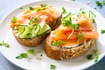 Open sandwich with cream cheese, salmon and cucumber in white plate. Healthy breakfast or snack. Close up.