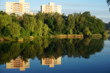 Fototapeta na wymiar Reflection of multi-storey buildings in the water of Morawa pond. Szopienice neighbourhood, Katowice, Poland.
