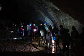 People with lanterns walk around the cave underground, a tourist group went on a tour of a large karst cave, Kapova Cave.