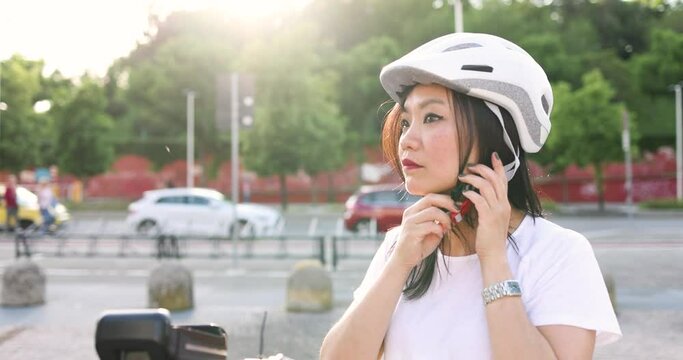 Businesswoman with e-scooter putting on safety helmet