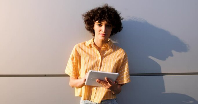 Pretty woman leaning against wall using digital tablet