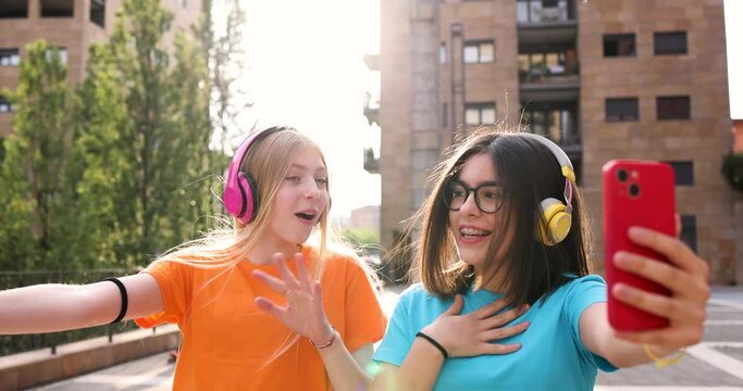 Happy girlfriends walking in the city taking smartphone selfies