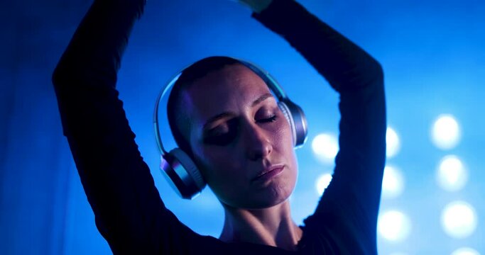 Woman wearing headphones moving dreamlike to music