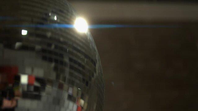 Narrow focus disco ball spins, reflecting light, copy space on right