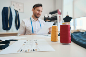 Man couturier sits at a table in a sewing workshop