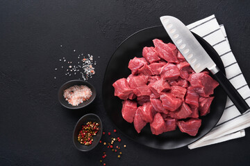 Raw chopped beef meat. Raw organic meat beef or lamb, spices, herbs on black plate on dark grey...